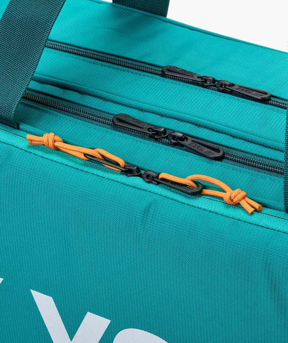 Close-up of Yonex Pro Tournament Bag BA92431W in Dark Green showing multiple zippered storage compartments and contrasting orange zipper pulls